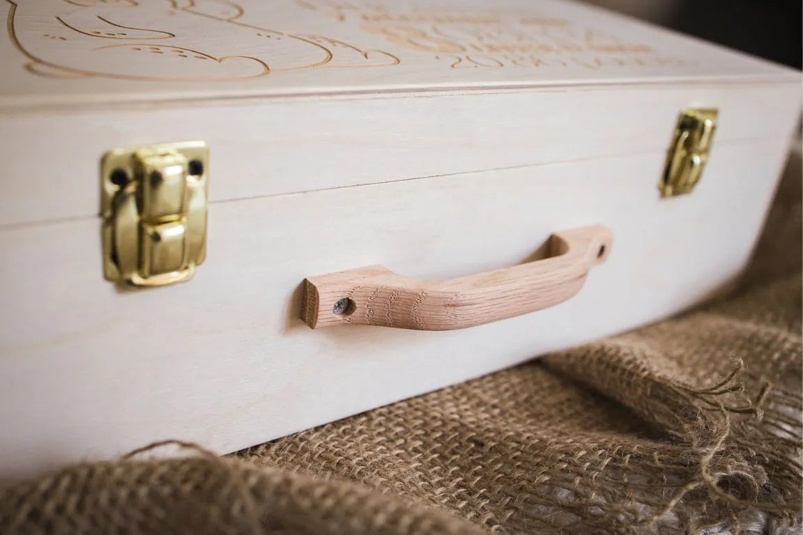La valise de naissance de Souvenirs du Hangar est réalisée en bois de bouleau et comprend une poignée en érable ainsi que des fermoirs plaqués laiton pour une finition impeccable et de qualité