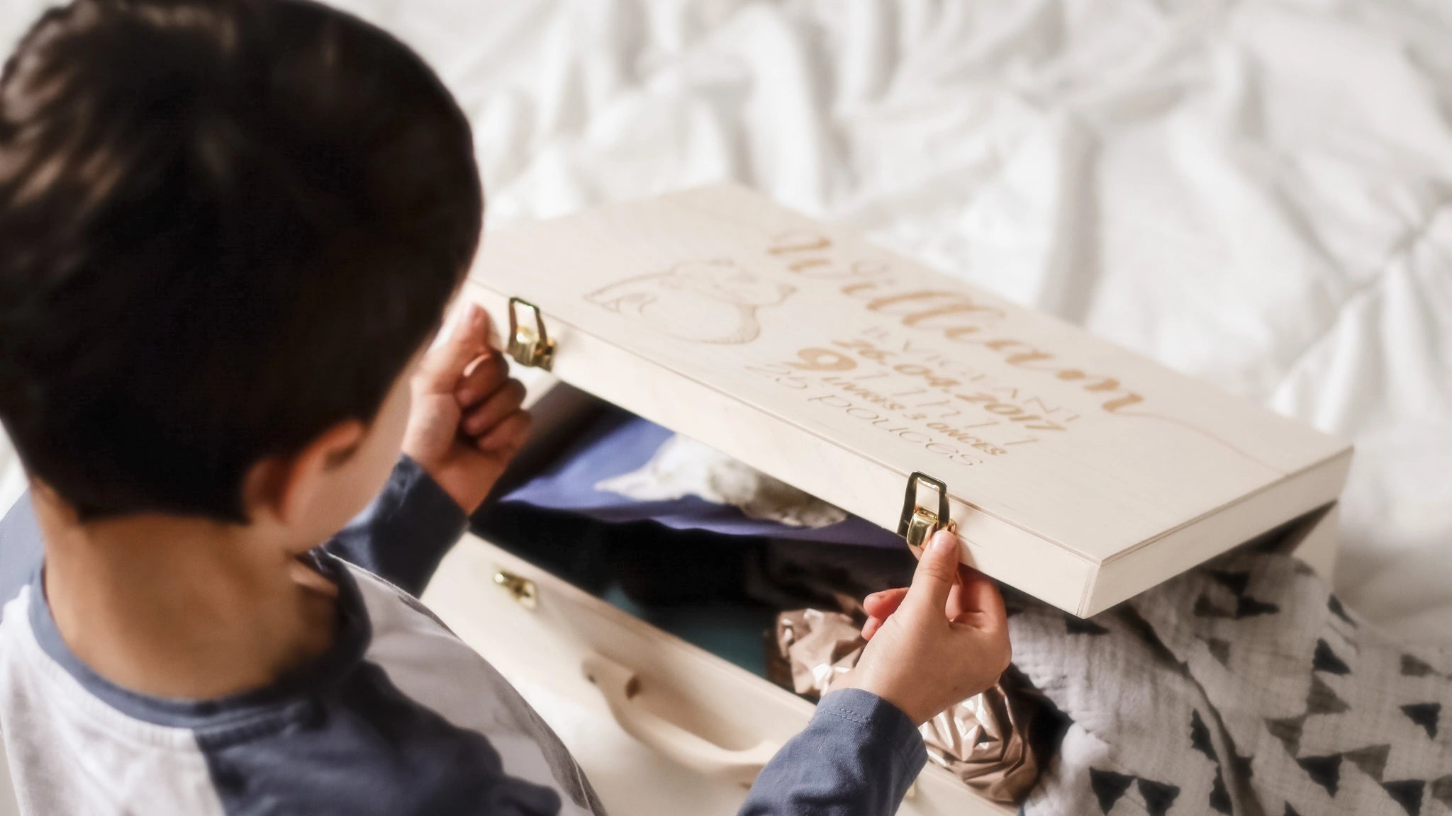 Un enfant et sa valise de souvenirs en bois personnalisée par un artisan québécois